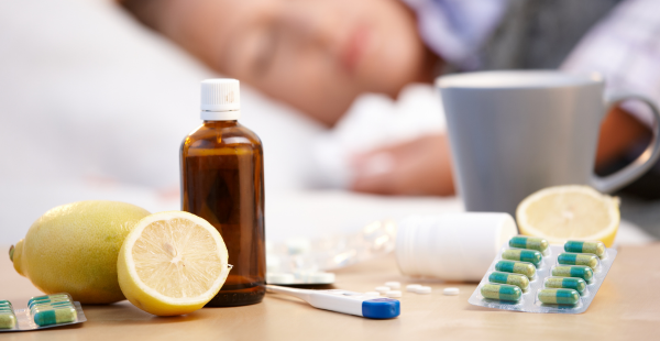 A row of cough and cold remedies on a table in front of a sleeping person.