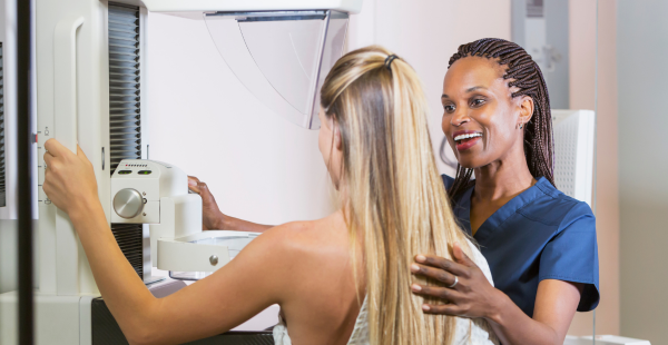 A health care professional setting up a mammogram with a patient.