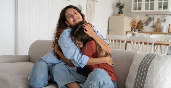 Une femme étreignant son enfant à la maison. 