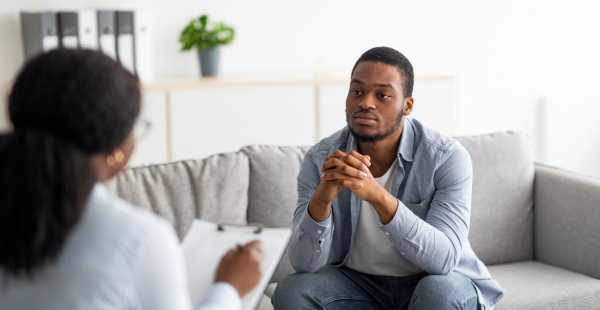 A man sitting on a sofa while engaged in a focused discussion with a healthcare provider.