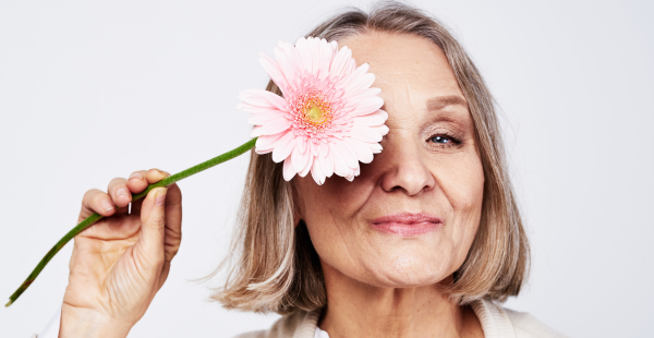 A woman of menopausal age smiling with a flower in her hand.